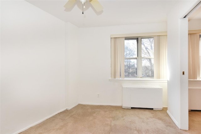 unfurnished room featuring carpet, baseboards, radiator heating unit, and a ceiling fan