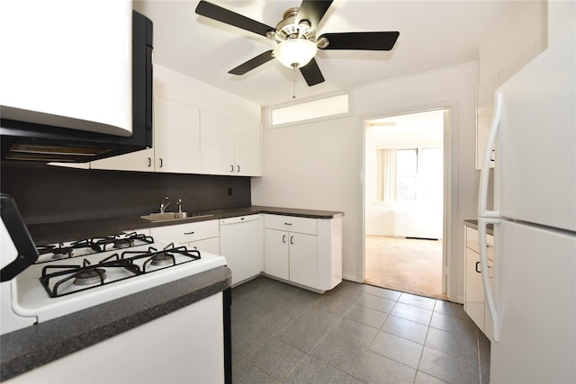 kitchen with white appliances, dark countertops, a sink, and white cabinetry