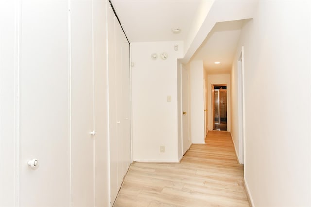 corridor with light wood-style flooring and baseboards