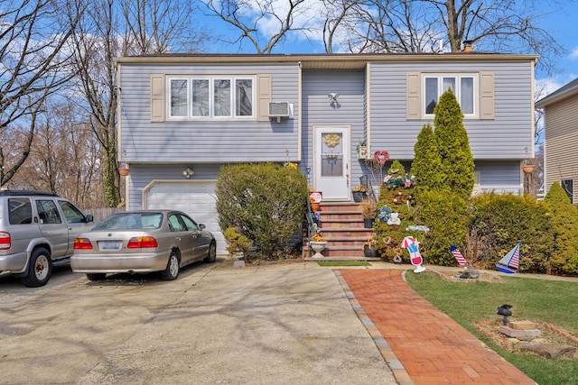 bi-level home with a garage, cooling unit, concrete driveway, and entry steps