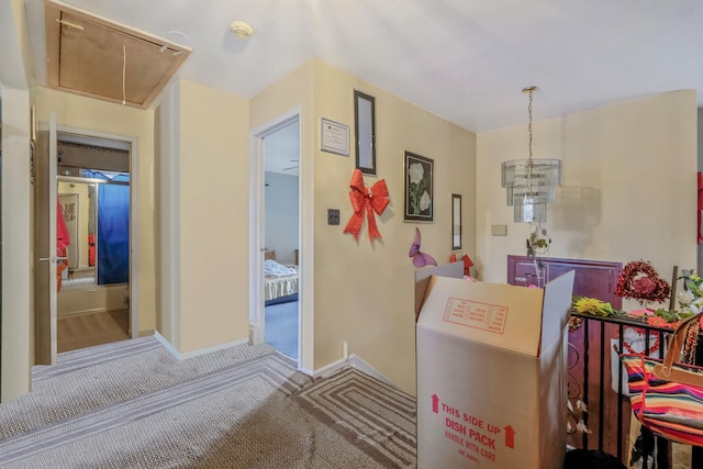 corridor with attic access, carpet flooring, and baseboards