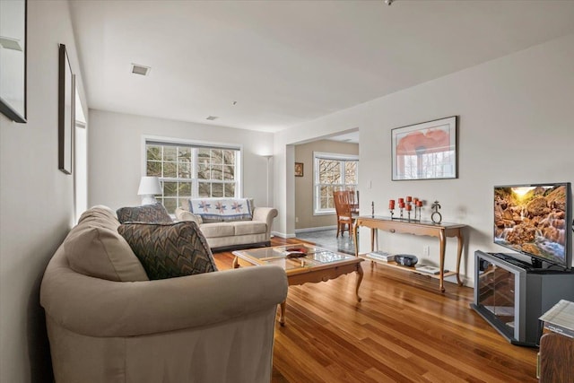 living room with visible vents, baseboards, and wood finished floors