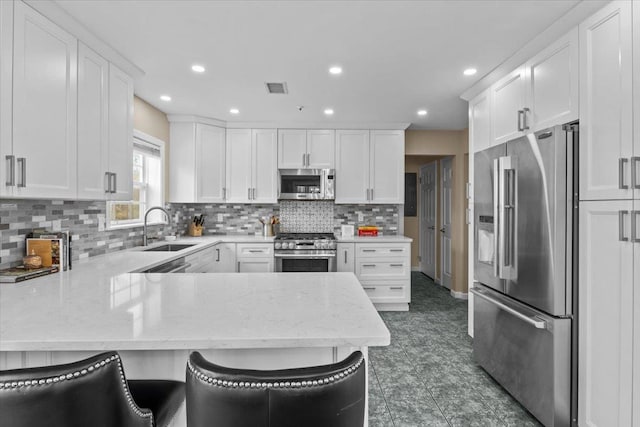 kitchen with visible vents, a sink, stainless steel appliances, a peninsula, and white cabinets