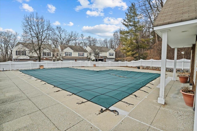 view of swimming pool featuring a patio, a fenced in pool, fence, and a residential view