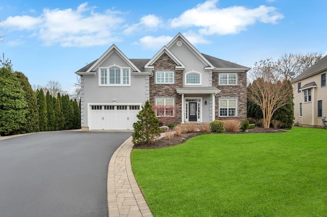 view of front of property featuring a front yard, stucco siding, a garage, stone siding, and aphalt driveway