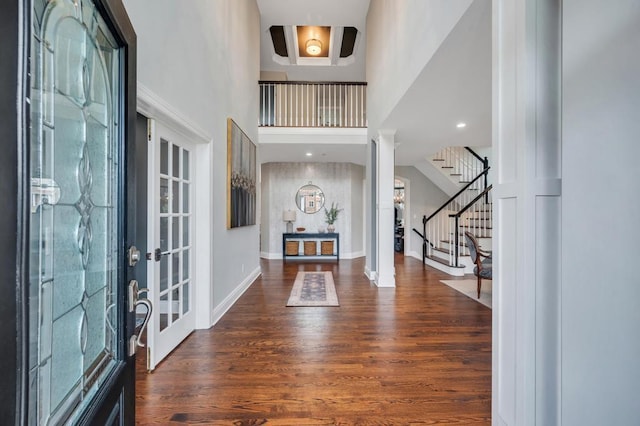 foyer with stairway, baseboards, wood finished floors, and ornate columns