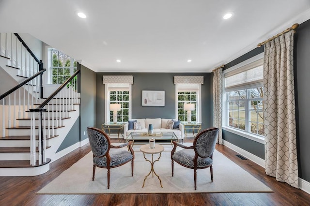 living area with crown molding, wood finished floors, baseboards, and visible vents