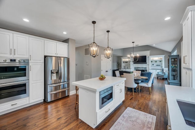 kitchen featuring dark wood-style flooring, a high end fireplace, stainless steel appliances, white cabinetry, and open floor plan