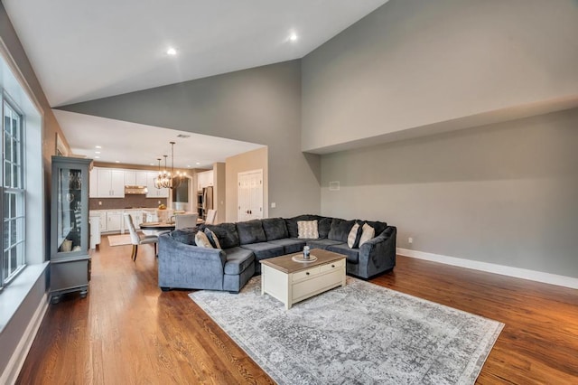 living area featuring baseboards, high vaulted ceiling, dark wood finished floors, recessed lighting, and a chandelier