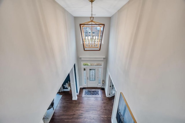 foyer featuring baseboards, a notable chandelier, a towering ceiling, and dark wood-style flooring