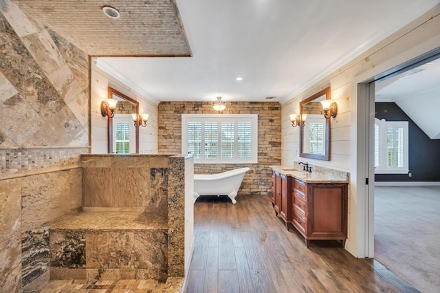 full bath with a soaking tub, vanity, wood finished floors, and ornamental molding