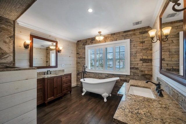 bathroom with vanity, a soaking tub, wood finished floors, and visible vents