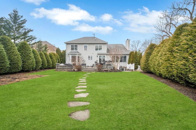 back of house featuring a yard and a chimney