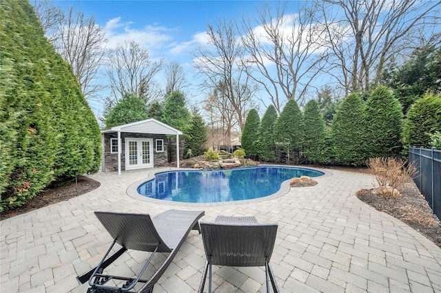 view of pool with a patio area, french doors, an outdoor structure, and a storage structure