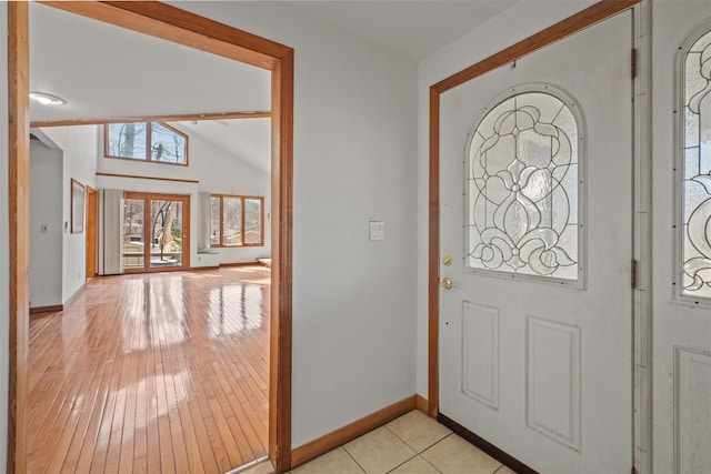 foyer entrance featuring light wood-type flooring, baseboards, and vaulted ceiling