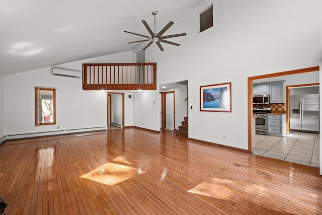 unfurnished living room featuring light wood finished floors, baseboard heating, a wall mounted AC, and a ceiling fan