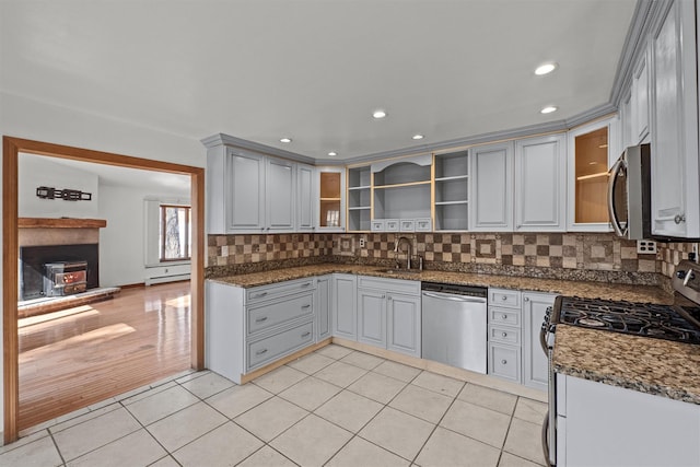 kitchen featuring light tile patterned floors, open shelves, a sink, appliances with stainless steel finishes, and tasteful backsplash