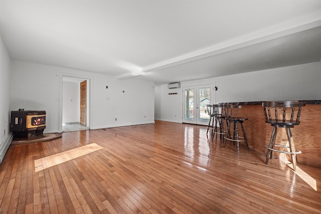 unfurnished living room with hardwood / wood-style floors, a wall unit AC, a wood stove, french doors, and a dry bar