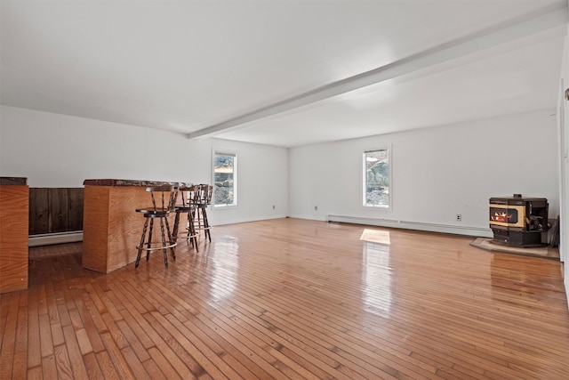 living area with a baseboard heating unit, beam ceiling, and hardwood / wood-style flooring