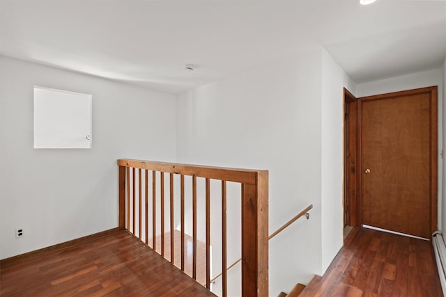 hallway with wood finished floors, an upstairs landing, and a baseboard radiator