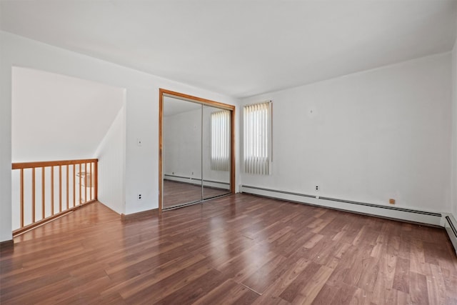 unfurnished bedroom featuring wood finished floors, a closet, and baseboard heating