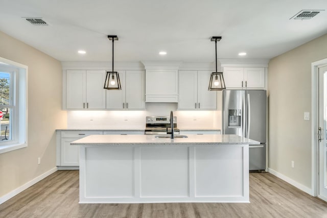 kitchen with stainless steel appliances, a center island with sink, a sink, and visible vents