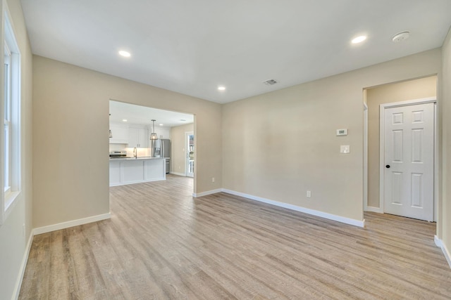 unfurnished living room featuring light wood finished floors, baseboards, and visible vents