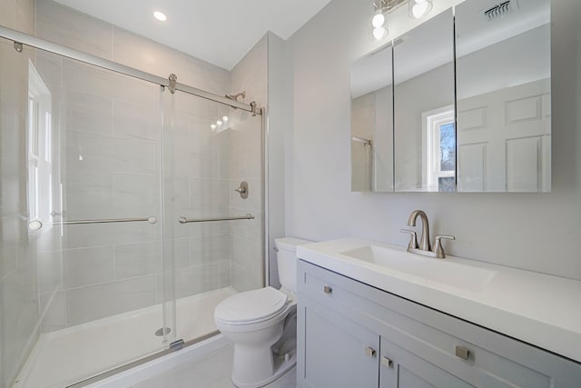 full bathroom featuring toilet, vanity, a shower stall, and visible vents