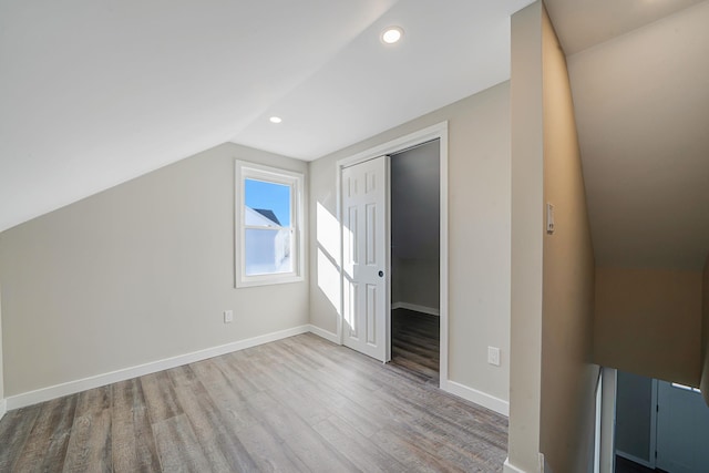 additional living space featuring baseboards, vaulted ceiling, wood finished floors, and recessed lighting