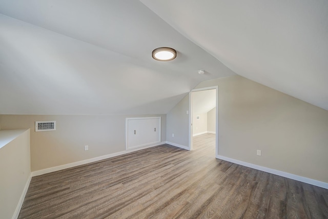 additional living space featuring visible vents, vaulted ceiling, baseboards, and wood finished floors