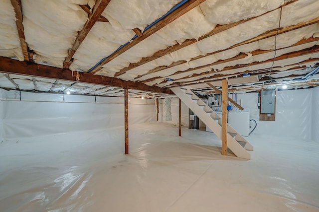 unfinished basement with washer / clothes dryer, electric panel, and stairway