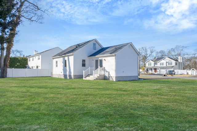 rear view of house featuring a yard and fence