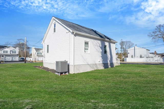 view of property exterior with a lawn, fence, and central AC unit