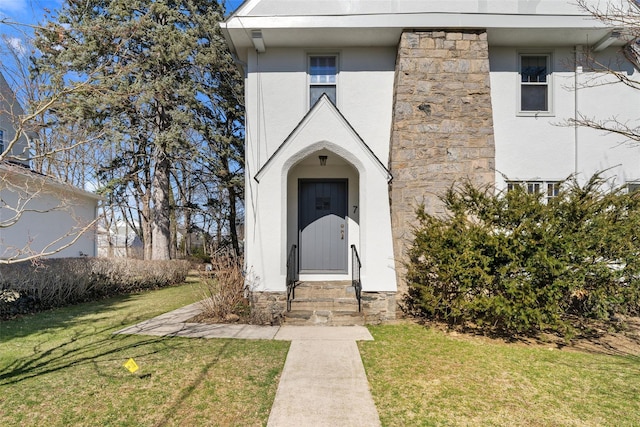 entrance to property featuring a lawn and stucco siding