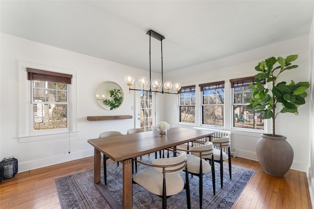 dining room with baseboards, wood-type flooring, and an inviting chandelier