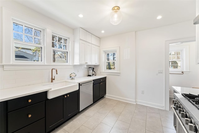 kitchen with a sink, white cabinetry, appliances with stainless steel finishes, decorative backsplash, and dark cabinets