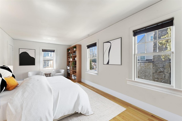 bedroom featuring multiple windows, baseboards, and light wood-type flooring