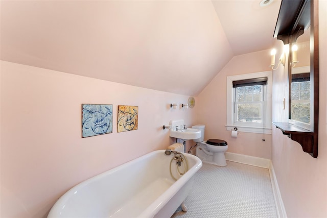 full bath with a freestanding tub, toilet, baseboards, and vaulted ceiling