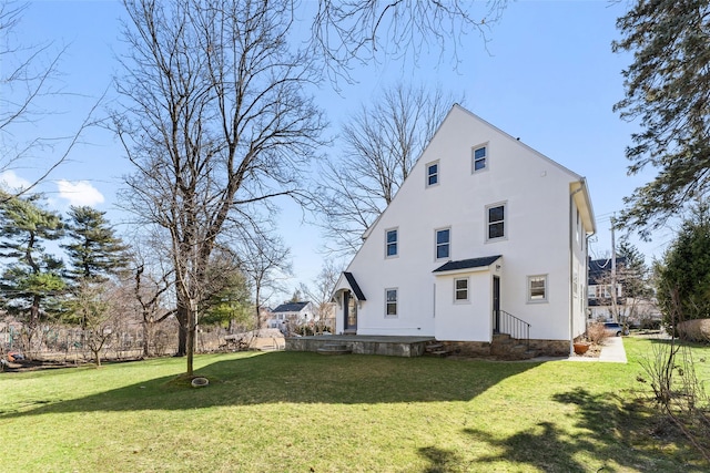 back of house with stucco siding and a lawn