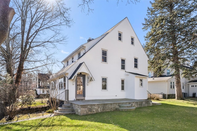 rear view of house with a patio, a yard, and stucco siding