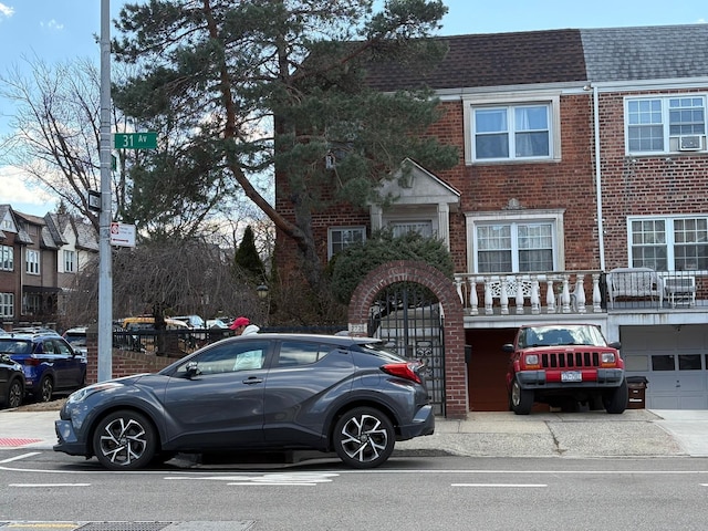 multi unit property featuring a shingled roof, brick siding, an attached garage, and mansard roof