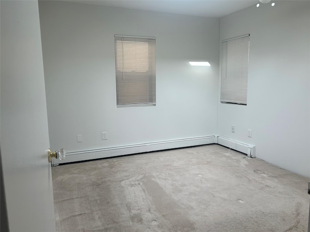 carpeted empty room featuring a baseboard heating unit