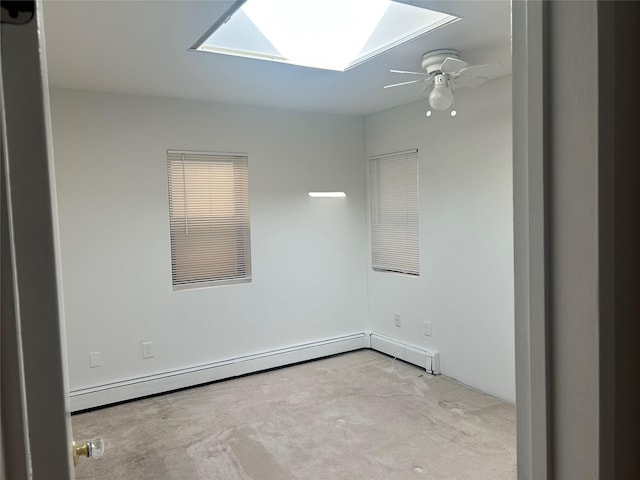 empty room featuring a skylight, ceiling fan, and a baseboard radiator