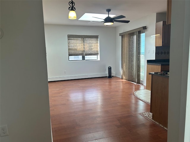 interior space featuring a baseboard radiator, a ceiling fan, a skylight, and dark wood-style flooring