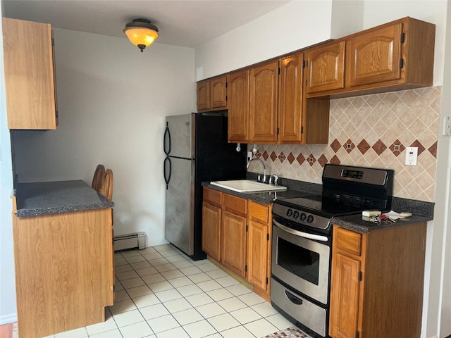 kitchen with a sink, dark countertops, appliances with stainless steel finishes, light tile patterned floors, and decorative backsplash