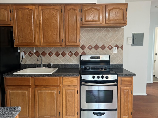 kitchen featuring stainless steel gas stove, a sink, electric panel, freestanding refrigerator, and decorative backsplash