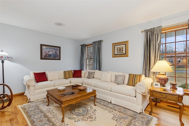 living room with visible vents, light wood-type flooring, and baseboards