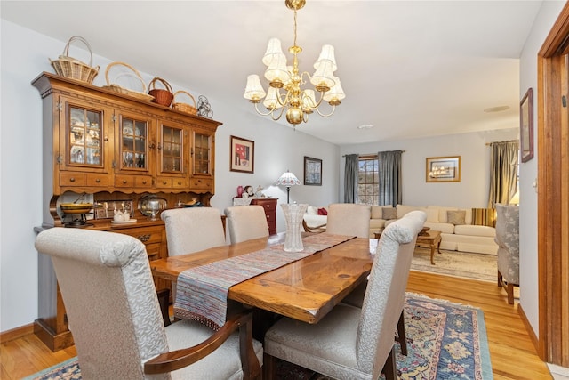 dining room with a chandelier, baseboards, and light wood-style flooring