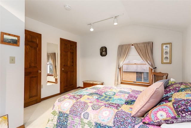 bedroom with carpet flooring, rail lighting, baseboards, and vaulted ceiling