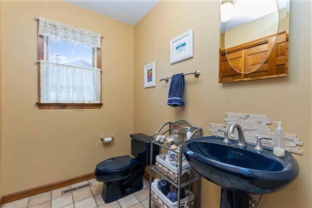 bathroom with baseboards, visible vents, a sink, tile patterned flooring, and toilet